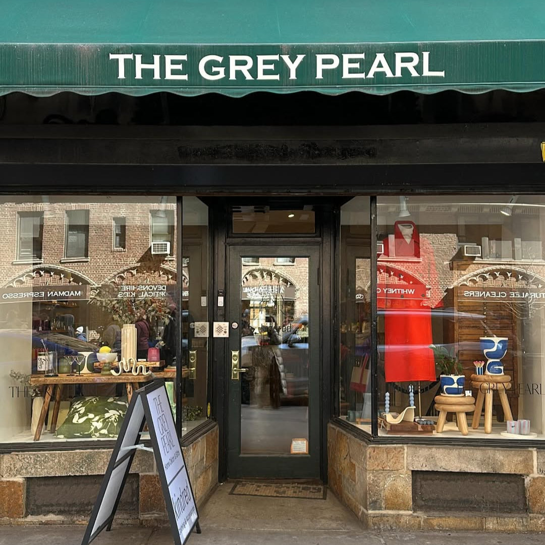 Storefront of 'The Grey Pearl' with a green awning and display windows.