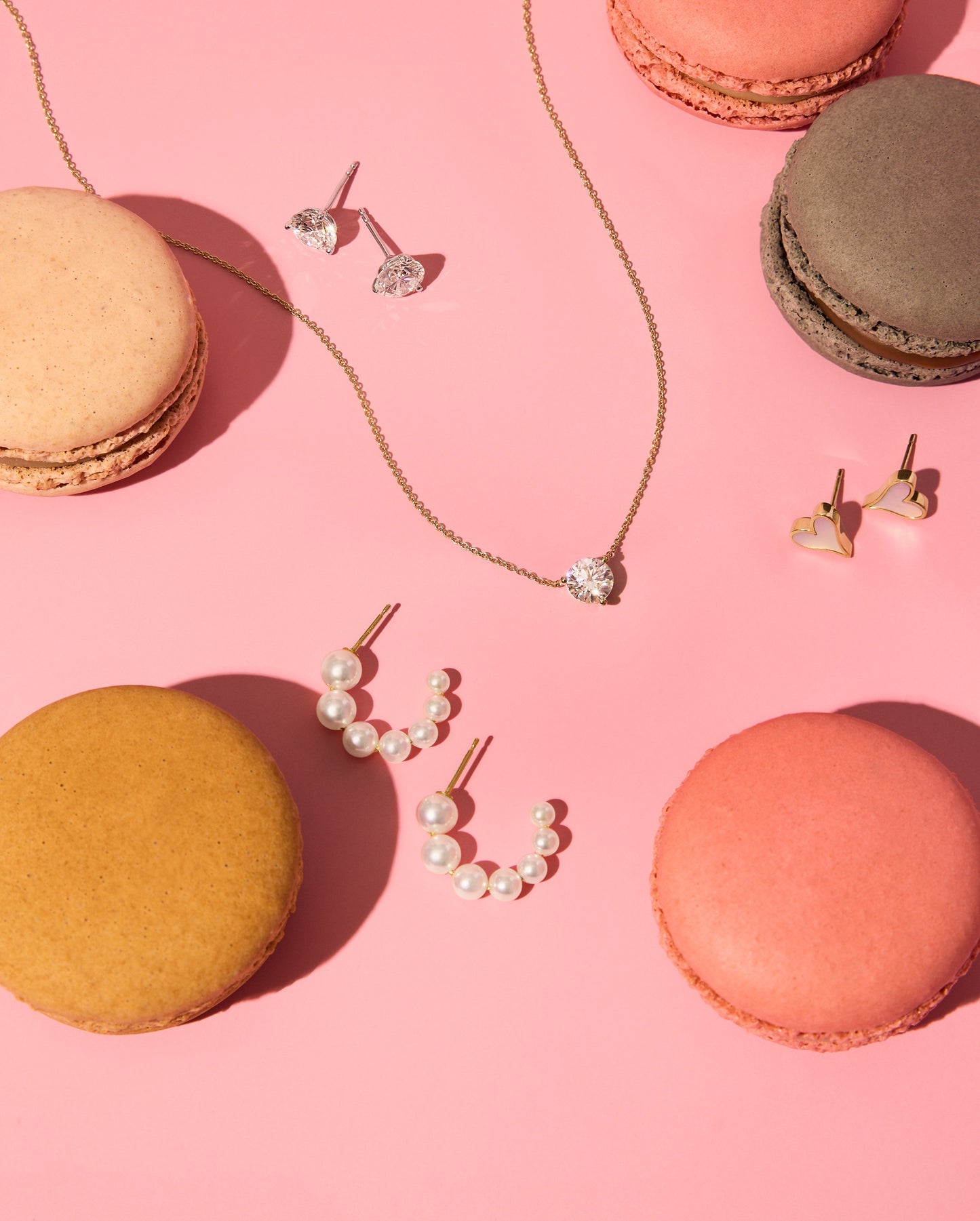 A stylized image featuring a pair of 18k yellow gold Akoya hoop earring, lab-grown diamond earrings and pendant, and Roseate Heart earrings.