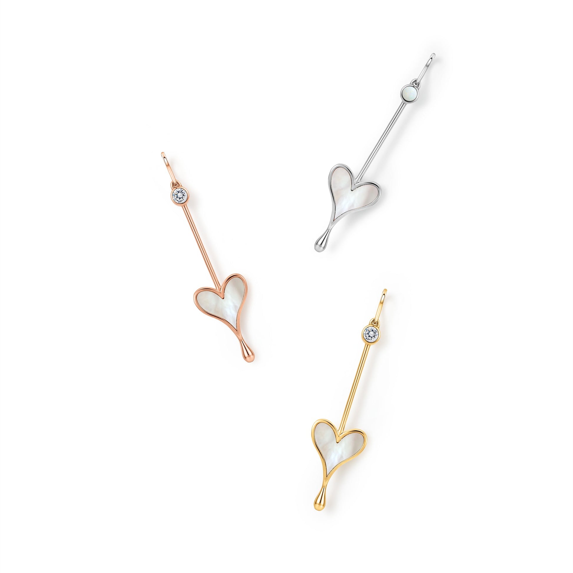 Three Love Wand pendants in gold, rose gold, and silver on a white background