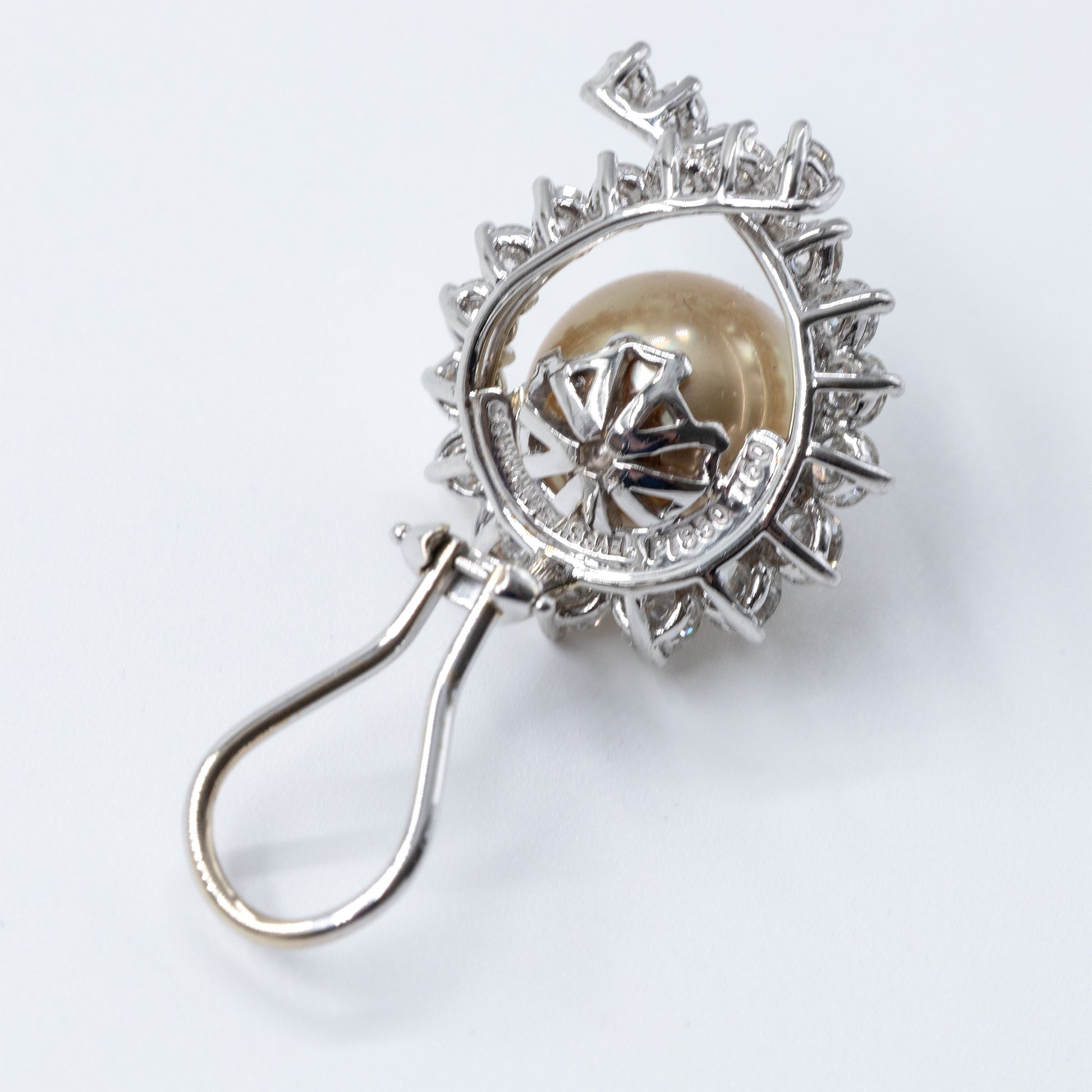Vintage Angela Cummings for Assael earrings featuring round Golden South Sea cultured pearls surrounded by brilliant-cut diamonds in platinum and 18K white gold.  Image shows back of earrings as clip on style and the Angela Cummings and PT 950 and  18k White Gold 750 metal markings. Offered by Roseate.Offered by Roseate.