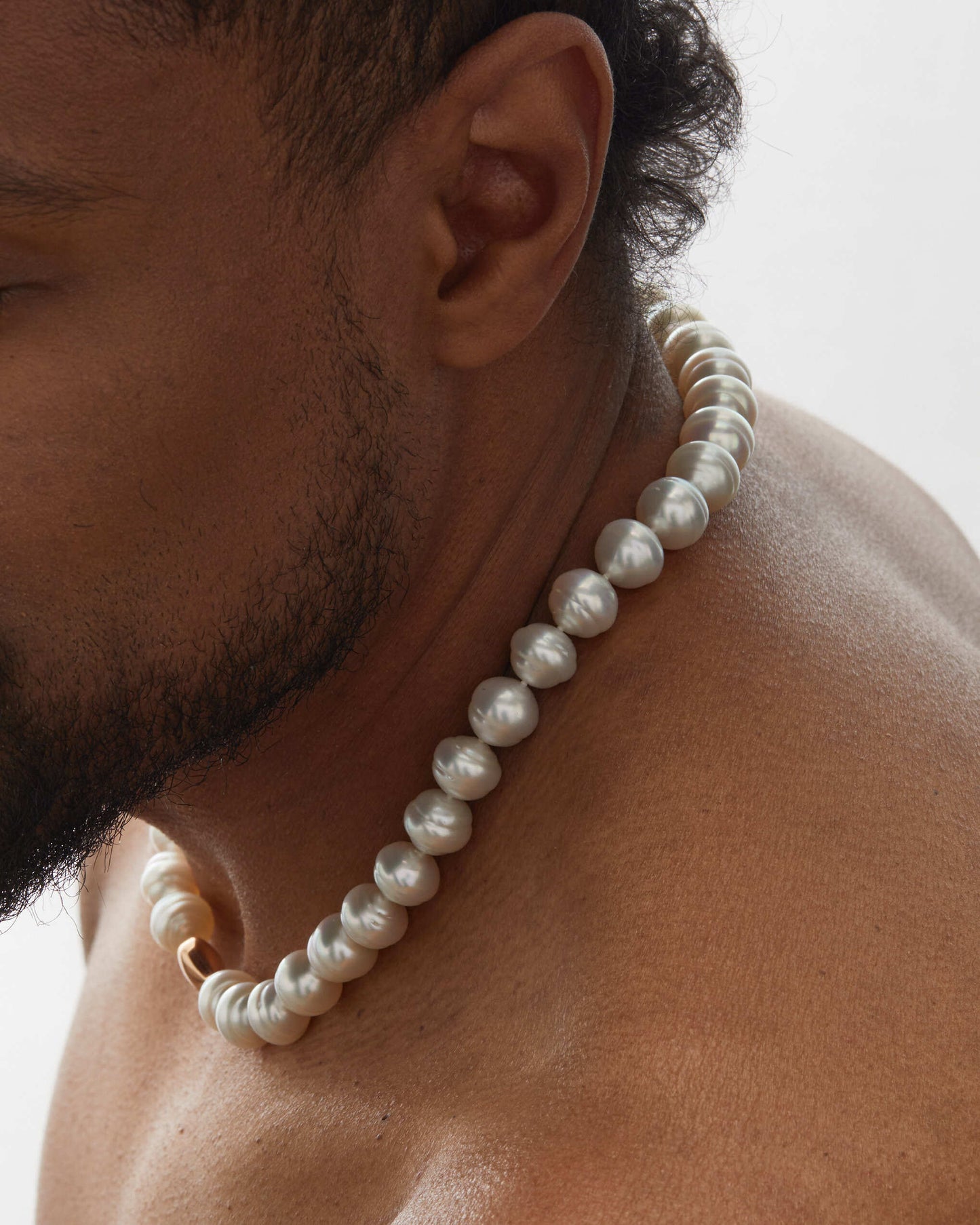 Roseate white Australian South Sea circle cultured pearl necklace featuring naturally luminous Paspaley pearls and an 18K rose gold clasp on a male model