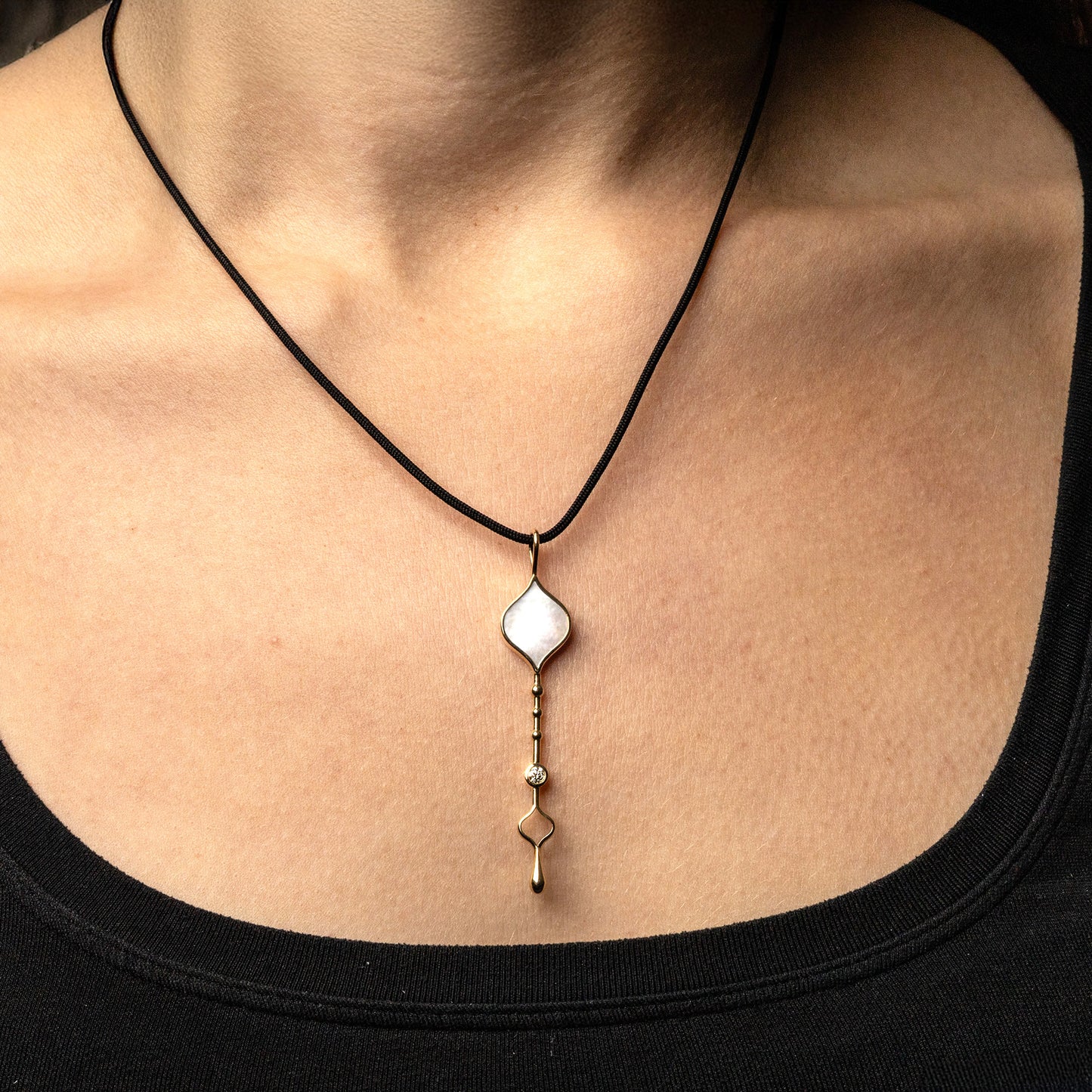 Unity Wand Pendant in 18K rose gold with luminous mother-of-pearl on a silk cord on model