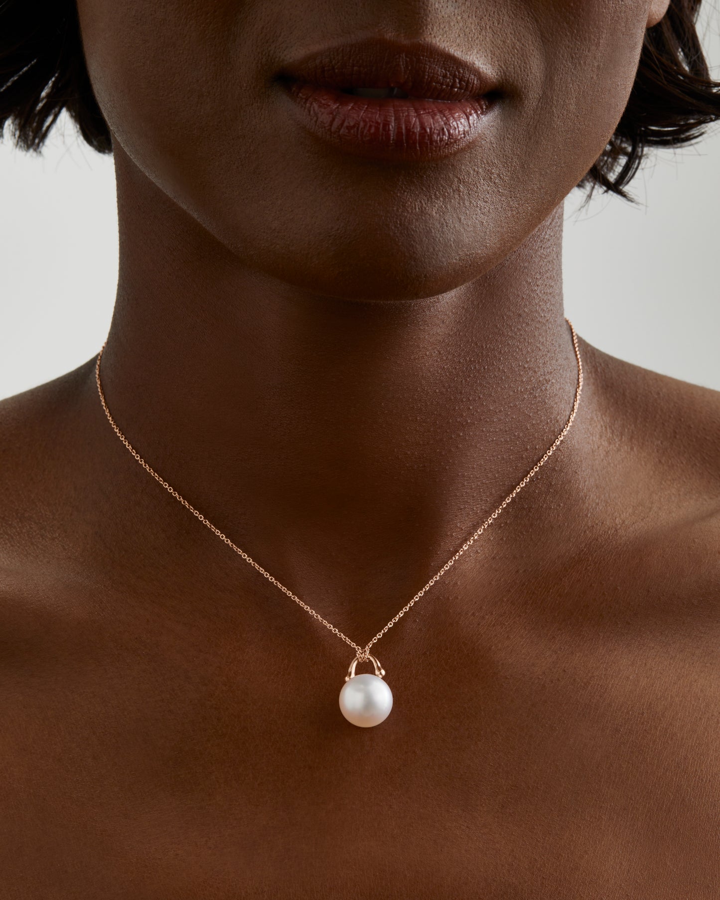 Roseate TreasureLock pendant featuring an 11mm white South Sea cultured pearl set in 18K yellow gold. Shown on model. A modern heirloom designed to showcase the exceptional beauty of a single South Sea pearl.
